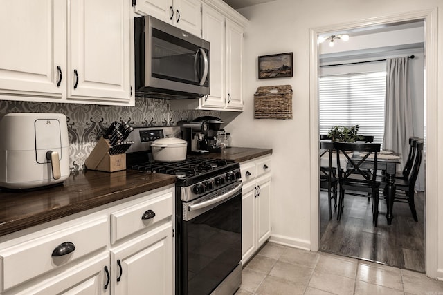 kitchen with tasteful backsplash, white cabinets, stainless steel appliances, and light wood-type flooring