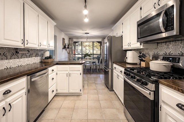 kitchen featuring light tile patterned flooring, white cabinetry, hanging light fixtures, and appliances with stainless steel finishes