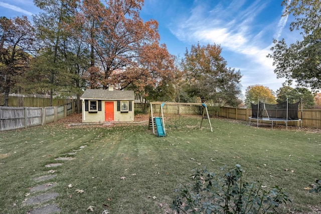 view of yard featuring a playground, an outbuilding, and a trampoline