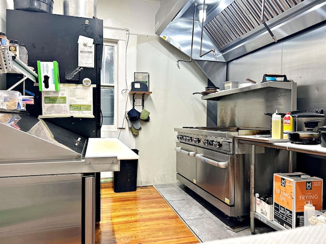 kitchen with wood-type flooring, exhaust hood, and high end range