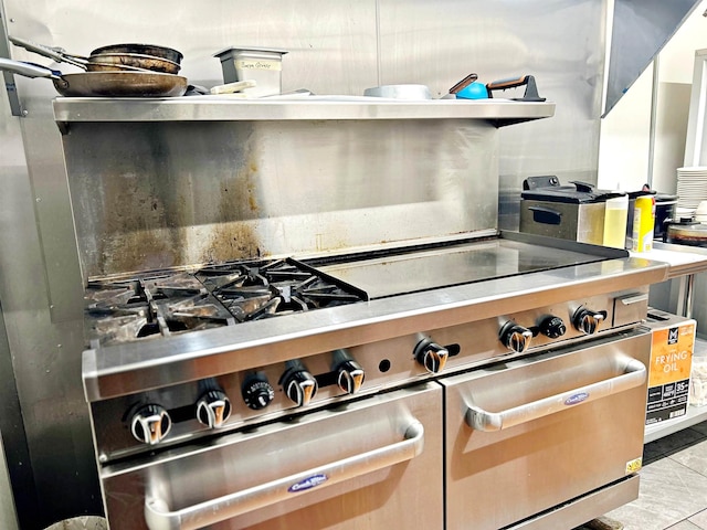 kitchen with backsplash, stainless steel stove, and light tile patterned floors