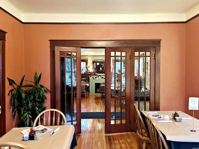 dining area featuring wood-type flooring, french doors, and ornamental molding