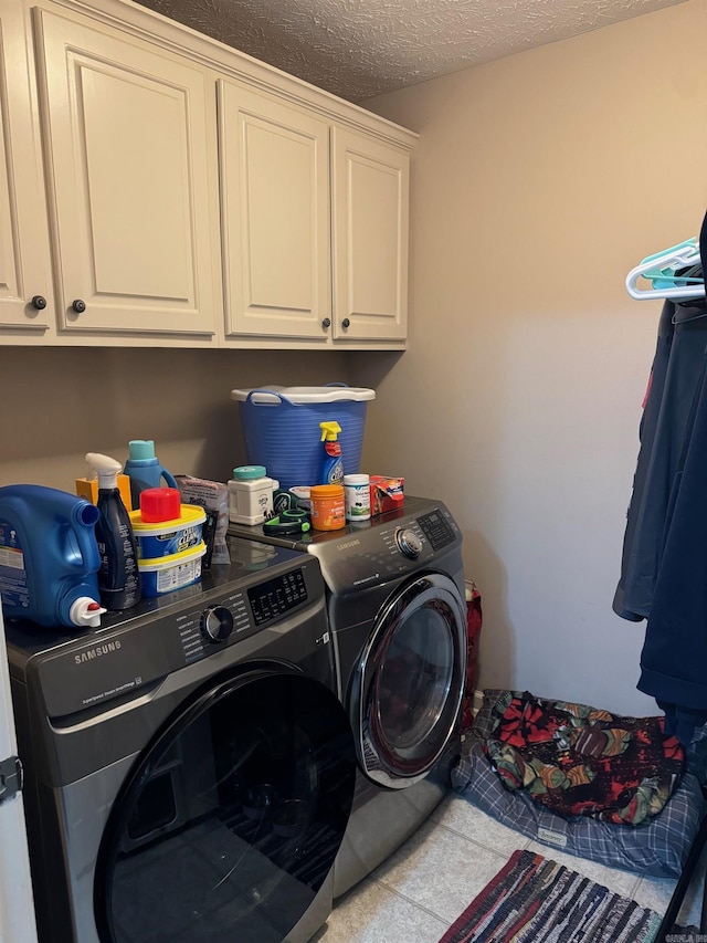 clothes washing area featuring washing machine and clothes dryer, cabinets, and a textured ceiling