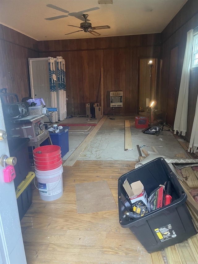 miscellaneous room featuring heating unit, wooden walls, and ceiling fan