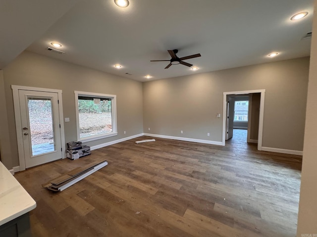 unfurnished living room with ceiling fan, a healthy amount of sunlight, and dark hardwood / wood-style floors