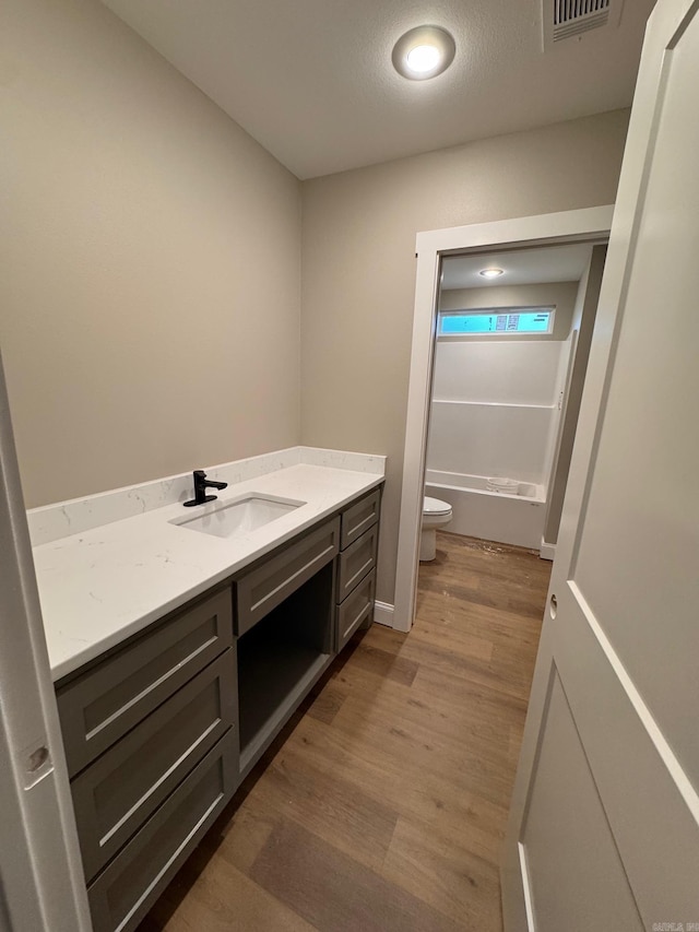 full bathroom with vanity, wood-type flooring,  shower combination, and toilet