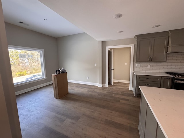 kitchen with dark hardwood / wood-style floors, tasteful backsplash, gray cabinetry, gas stove, and wall chimney exhaust hood