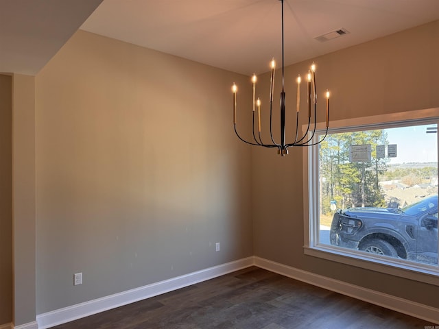 spare room featuring dark hardwood / wood-style floors and a chandelier