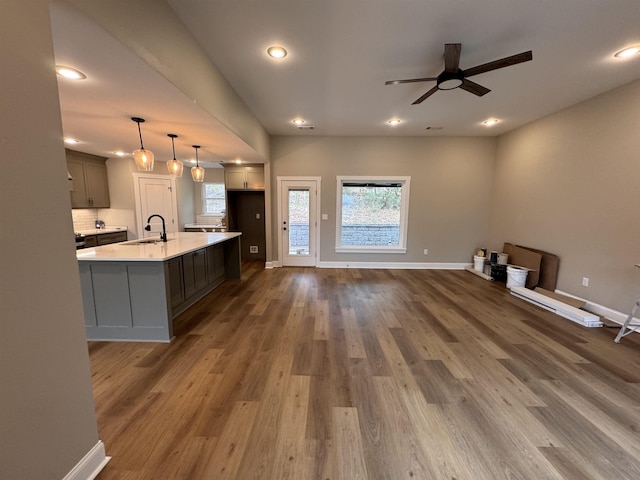 kitchen with dark wood-type flooring, sink, decorative light fixtures, an island with sink, and ceiling fan