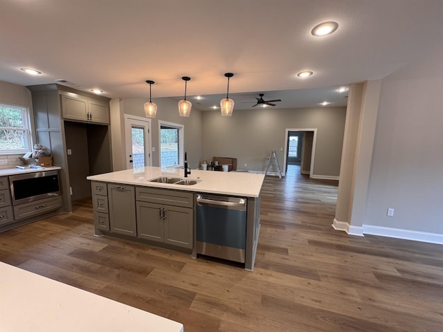 kitchen featuring pendant lighting, sink, gray cabinetry, a kitchen island with sink, and stainless steel appliances