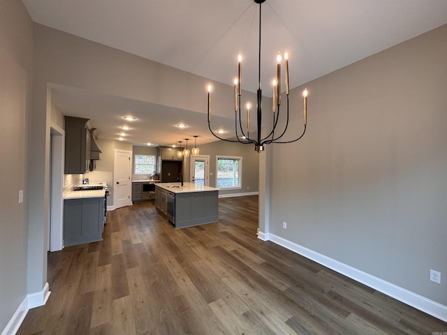 kitchen with pendant lighting, dark wood-type flooring, a kitchen island with sink, and gray cabinetry