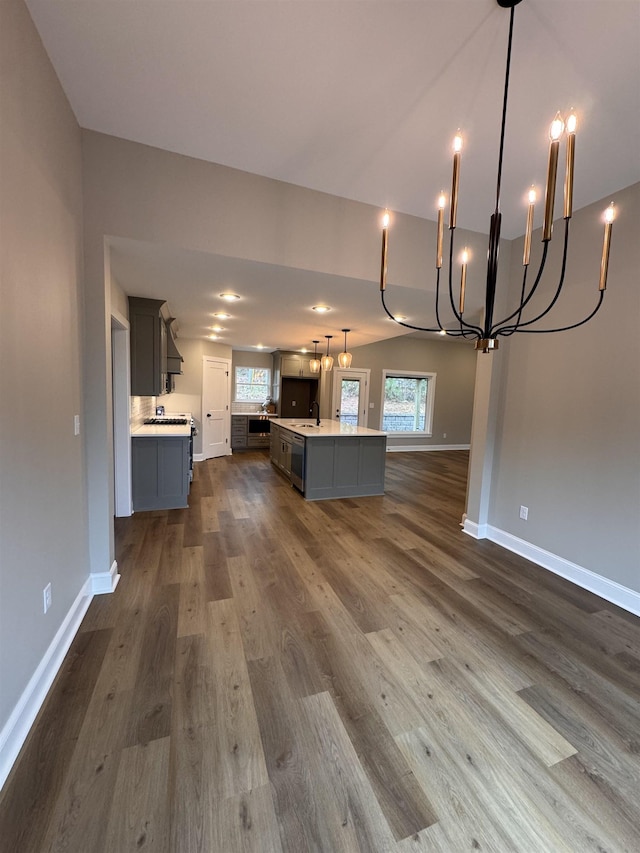 kitchen featuring sink, gray cabinets, a kitchen island with sink, dark hardwood / wood-style floors, and decorative light fixtures