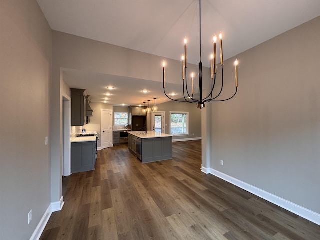 kitchen featuring sink, gray cabinetry, a center island with sink, dark hardwood / wood-style flooring, and decorative light fixtures