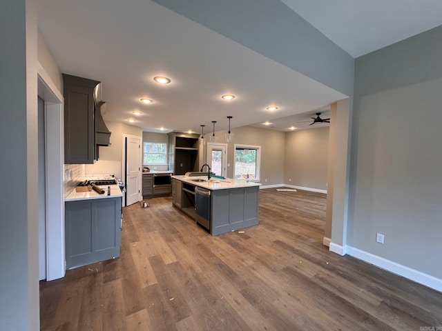 kitchen featuring dark hardwood / wood-style floors, sink, hanging light fixtures, a kitchen island with sink, and stainless steel dishwasher