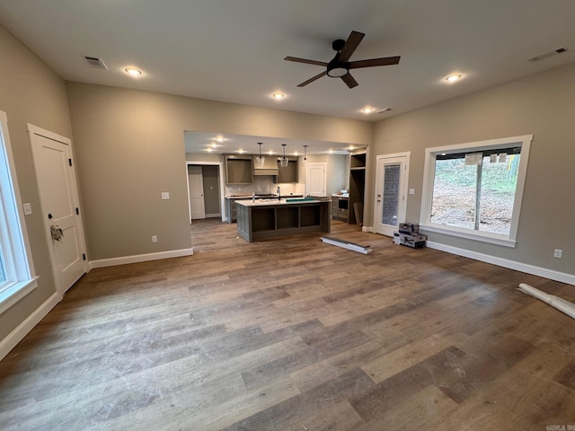 kitchen featuring a kitchen island with sink, hardwood / wood-style flooring, decorative light fixtures, and ceiling fan