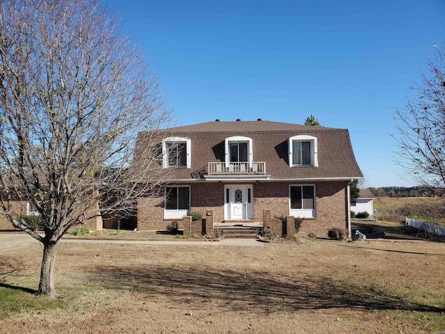 view of front of property with a balcony and a front lawn