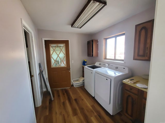 laundry room featuring washing machine and clothes dryer, dark hardwood / wood-style flooring, and cabinets