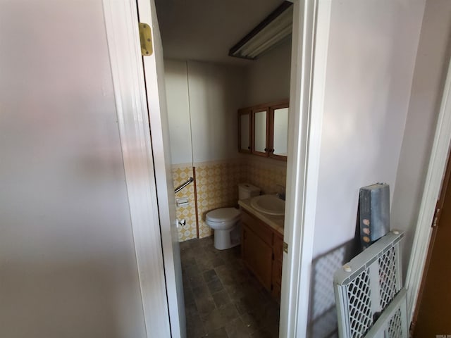 bathroom featuring vanity, tile walls, and toilet