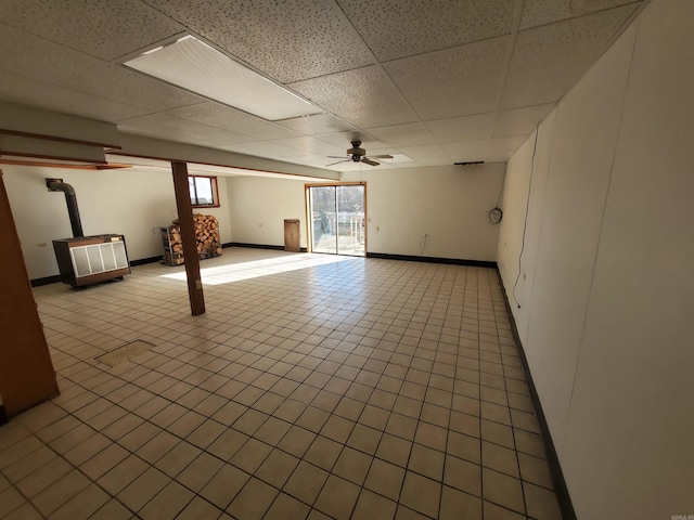 basement featuring a paneled ceiling, ceiling fan, and light tile patterned floors