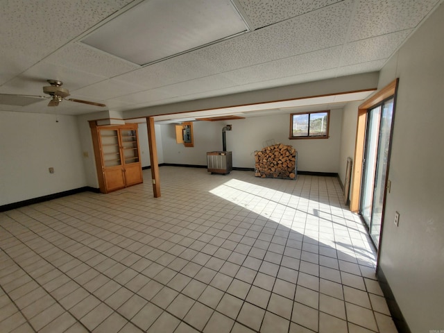 basement with a paneled ceiling, ceiling fan, and light tile patterned flooring