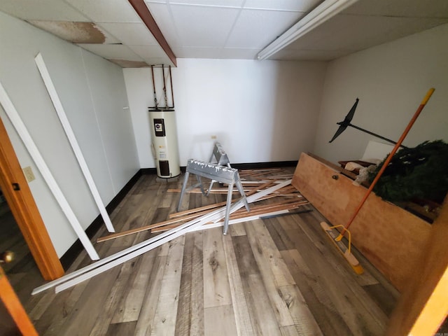 exercise area featuring electric water heater, a drop ceiling, and dark wood-type flooring