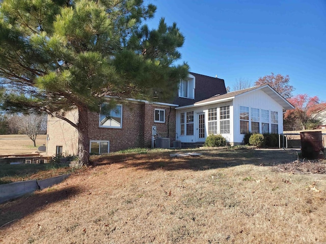 rear view of property with central AC and a yard