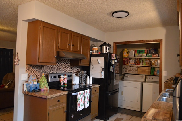 kitchen featuring stainless steel range with electric stovetop, under cabinet range hood, freestanding refrigerator, separate washer and dryer, and decorative backsplash