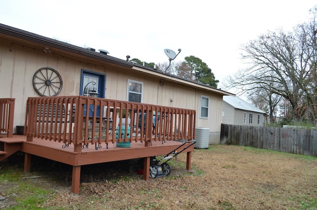 rear view of house featuring a wooden deck, a yard, and fence