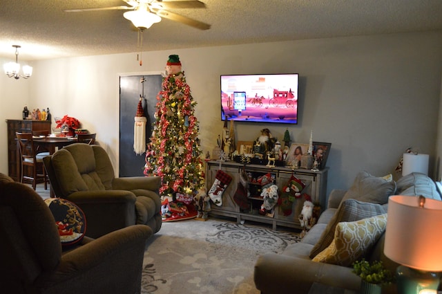 living room featuring carpet flooring, a textured ceiling, and ceiling fan with notable chandelier