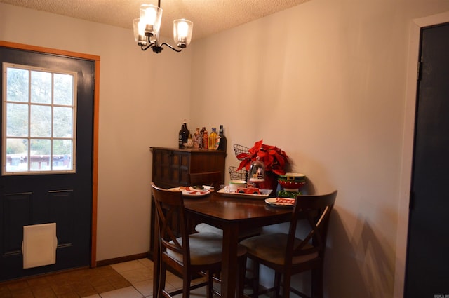 dining space with light tile patterned floors, a notable chandelier, a textured ceiling, and baseboards