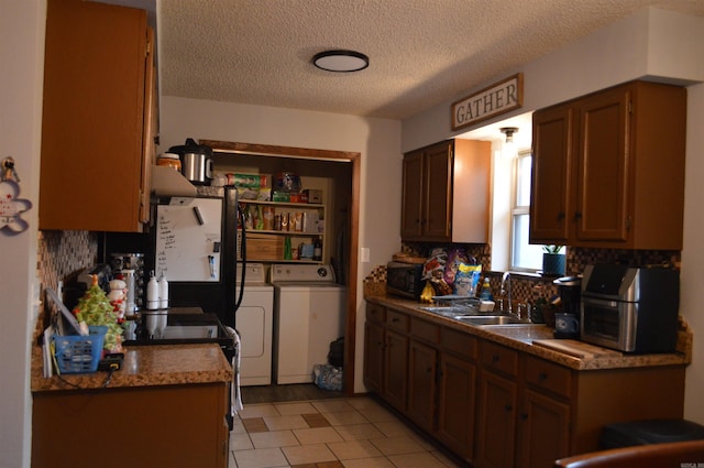 kitchen with washing machine and clothes dryer, tasteful backsplash, electric stove, a textured ceiling, and a sink