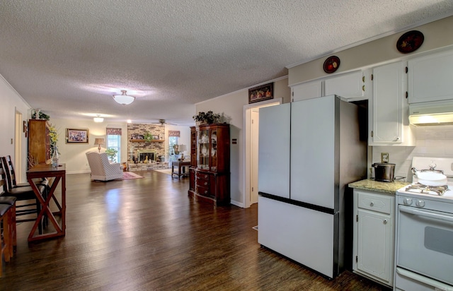 kitchen with white appliances, dark wood-type flooring, a brick fireplace, white cabinetry, and extractor fan