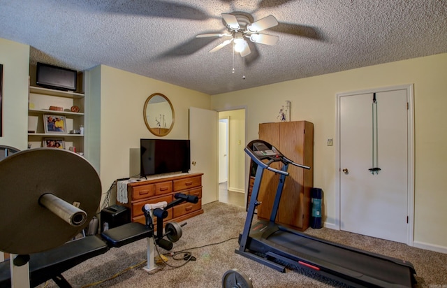 workout area featuring a textured ceiling, light colored carpet, and ceiling fan