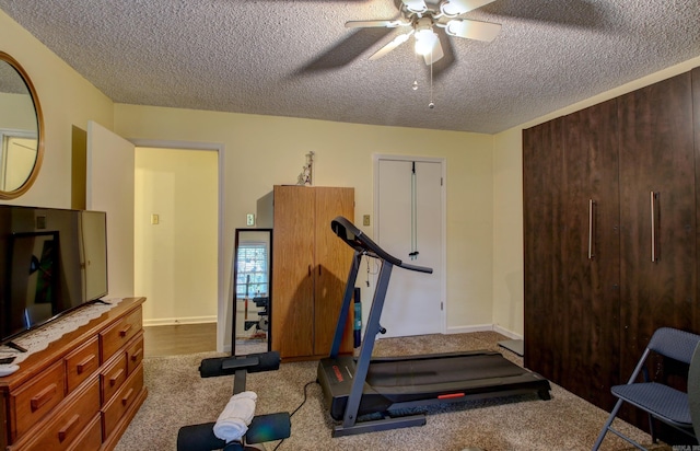 workout room featuring ceiling fan, carpet, and a textured ceiling