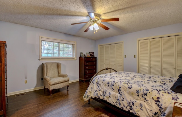 bedroom featuring ceiling fan, dark hardwood / wood-style flooring, a textured ceiling, and two closets