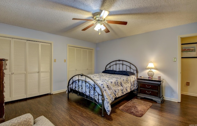 bedroom featuring two closets, a textured ceiling, dark hardwood / wood-style floors, and ceiling fan