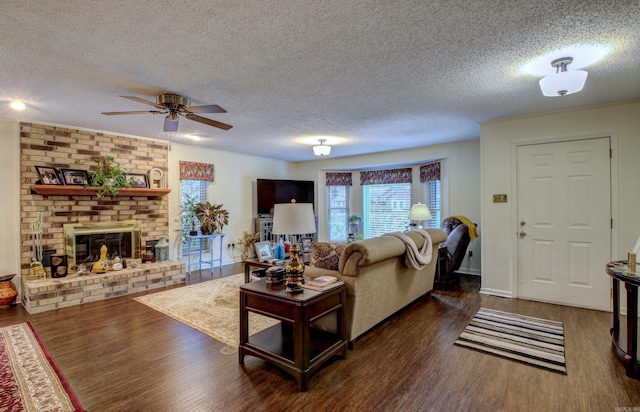 living room with a fireplace, ceiling fan, a textured ceiling, and dark wood-type flooring