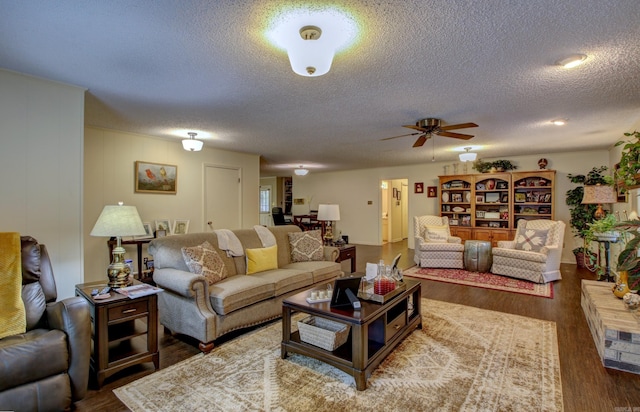 living room featuring dark hardwood / wood-style floors, ceiling fan, and a textured ceiling