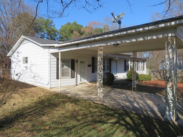 view of front of home with covered porch, a front yard, and a carport