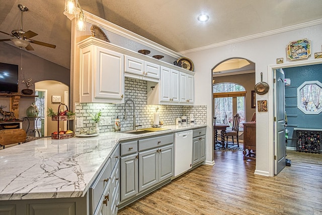 kitchen with dishwasher, sink, vaulted ceiling, light wood-type flooring, and ornamental molding