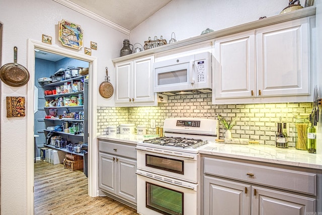 kitchen featuring lofted ceiling, backsplash, white appliances, crown molding, and light hardwood / wood-style flooring