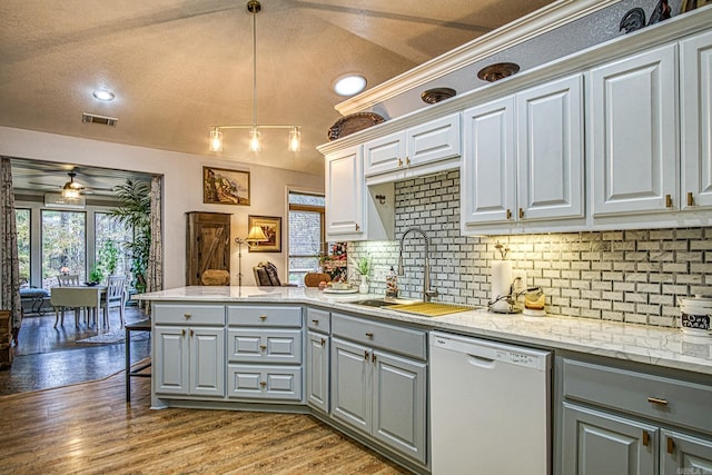 kitchen featuring sink, white dishwasher, pendant lighting, a textured ceiling, and hardwood / wood-style flooring