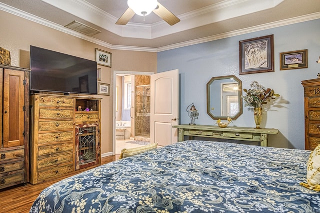 bedroom with crown molding, ensuite bath, hardwood / wood-style flooring, ceiling fan, and a tray ceiling