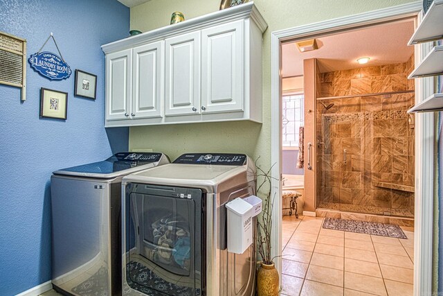 laundry area with washing machine and clothes dryer, light tile patterned floors, and cabinets