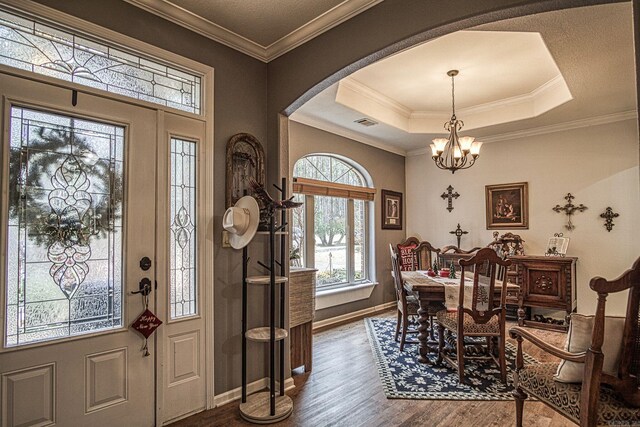 foyer entrance with a raised ceiling, crown molding, a chandelier, and dark hardwood / wood-style floors