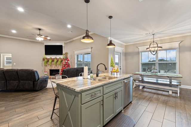 kitchen featuring dishwasher, sink, light stone counters, pendant lighting, and a center island with sink