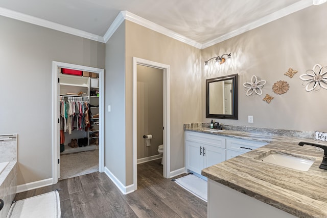 bathroom with ornamental molding, a washtub, vanity, hardwood / wood-style flooring, and toilet