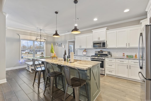 kitchen featuring white cabinetry, an island with sink, stainless steel appliances, and decorative light fixtures