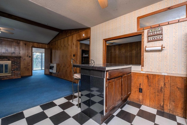 kitchen featuring dark colored carpet, lofted ceiling with beams, heating unit, and wood walls