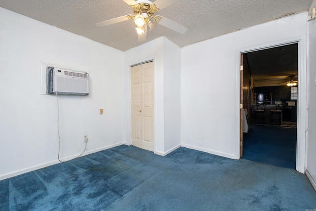 carpeted spare room featuring a textured ceiling, a wall unit AC, and ceiling fan